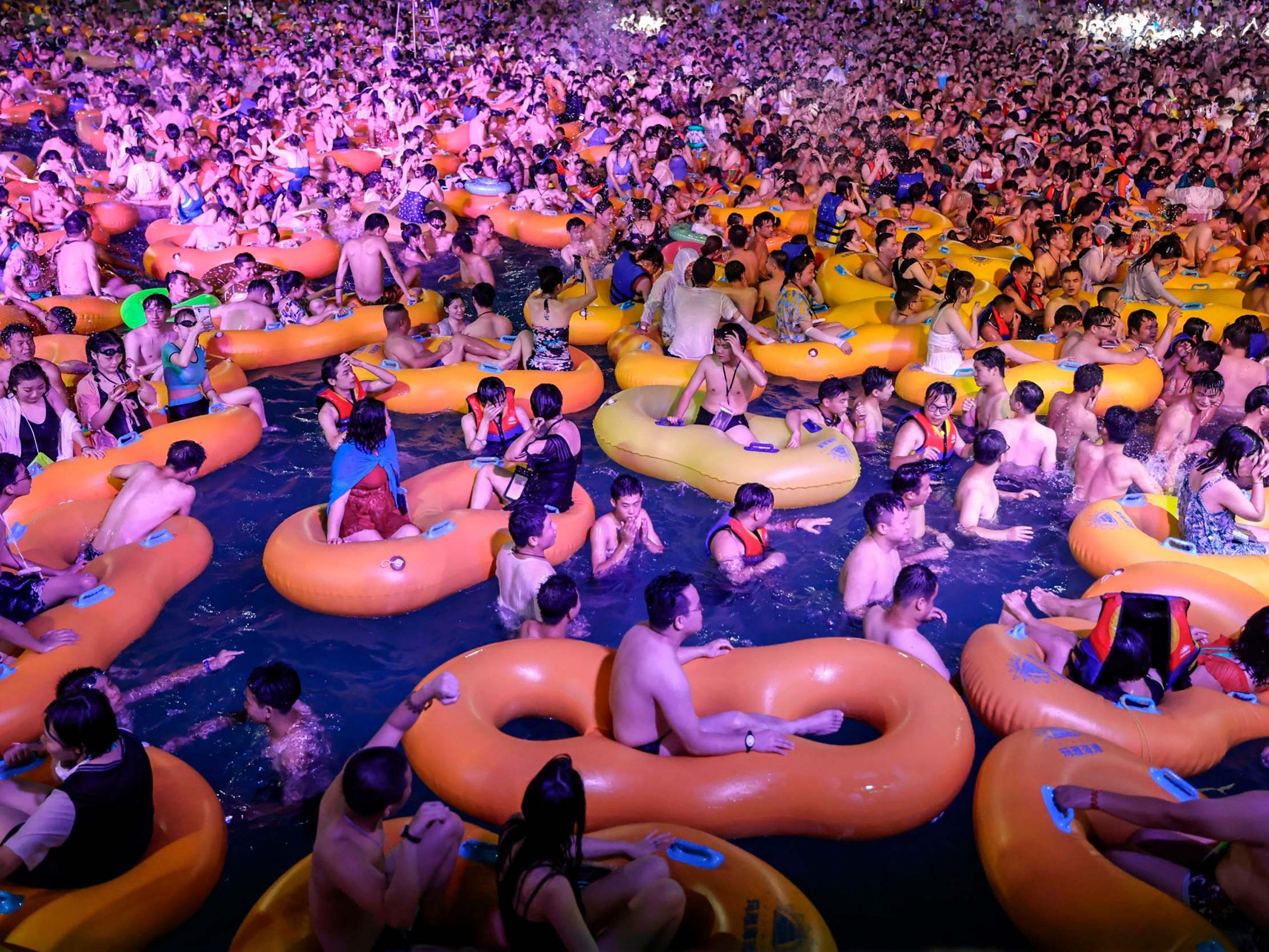People watching a performance as they cool off in a swimming pool in Wuhan