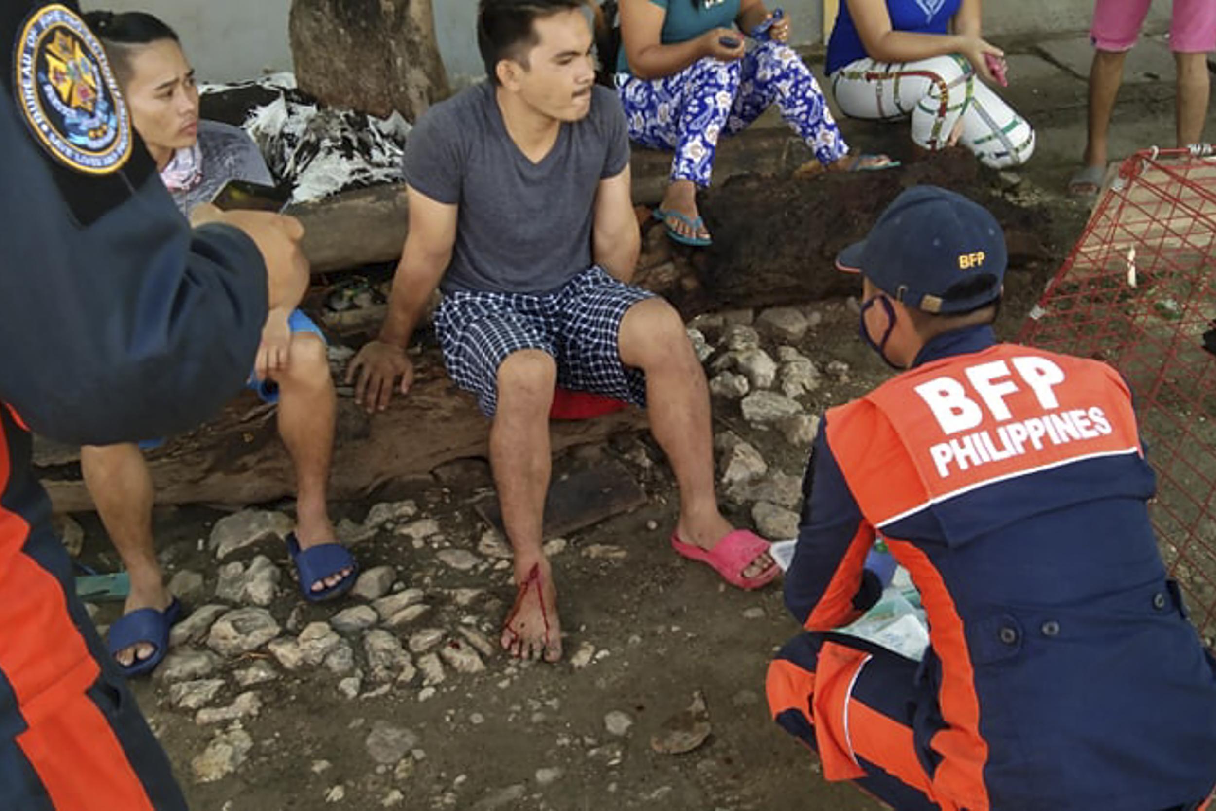 An injured man is treated by a Bureau of Fire Protection officer in Cataingan