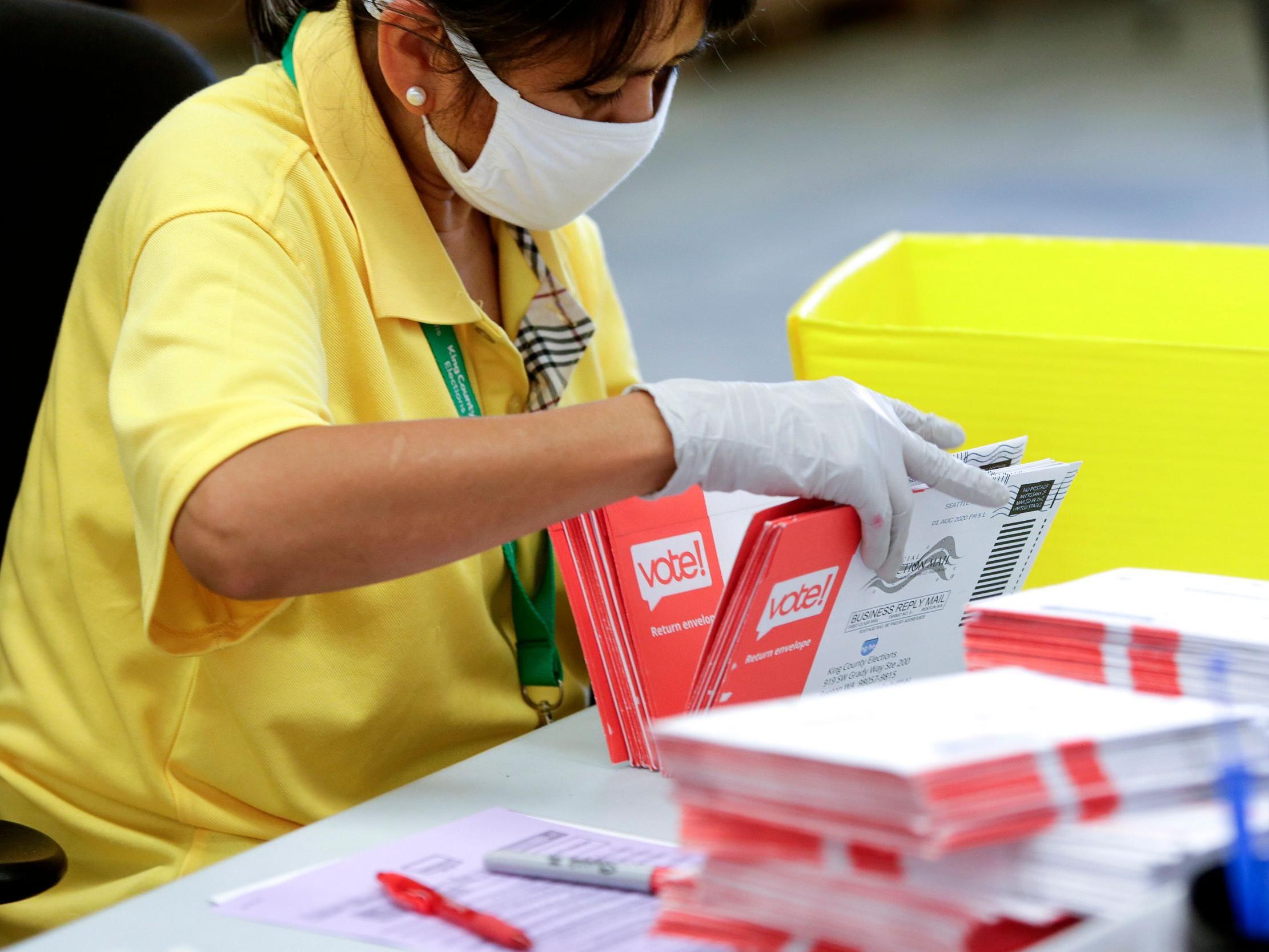 An election worker opens envelopes containing vote-by-mail ballots for the 4 August Washington state primary at King County Elections in Renton, Washington
