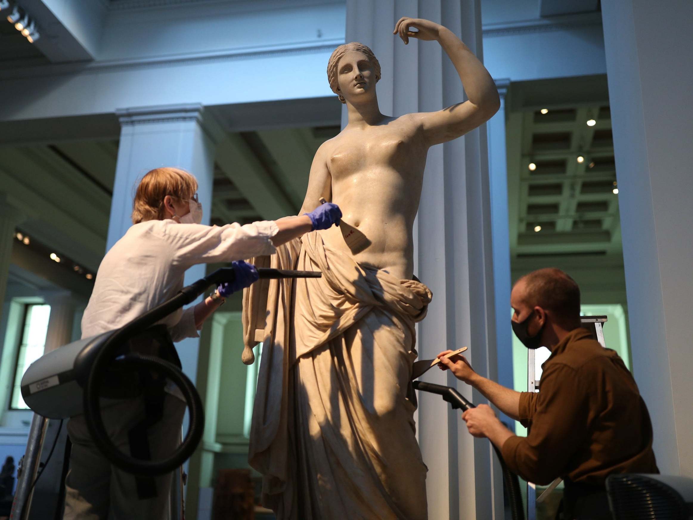 The collections team dust the Townley Venus Roman sculpture in the museum’s Greek and Roman sculpture gallery