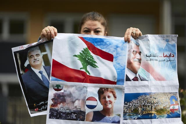 A supporter of former Prime Minister Rafiq Hariri holds posters outside the Lebanon Tribunal on August 18, 2020 in The Hague, Netherland