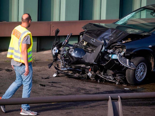 Police officer walks past battered motorcycle and car after a series of crashes on the Berlin motorway