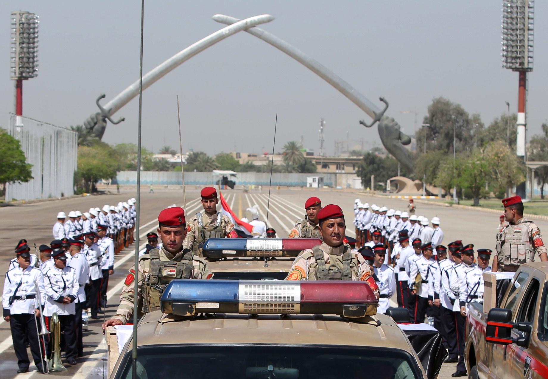 File: Iraqi soldiers drive in front of the Swords of Qadisiyah monument in Baghdad during a 2015 funeral parade. The swords are held in forearms modelled on Saddam Hussein's own