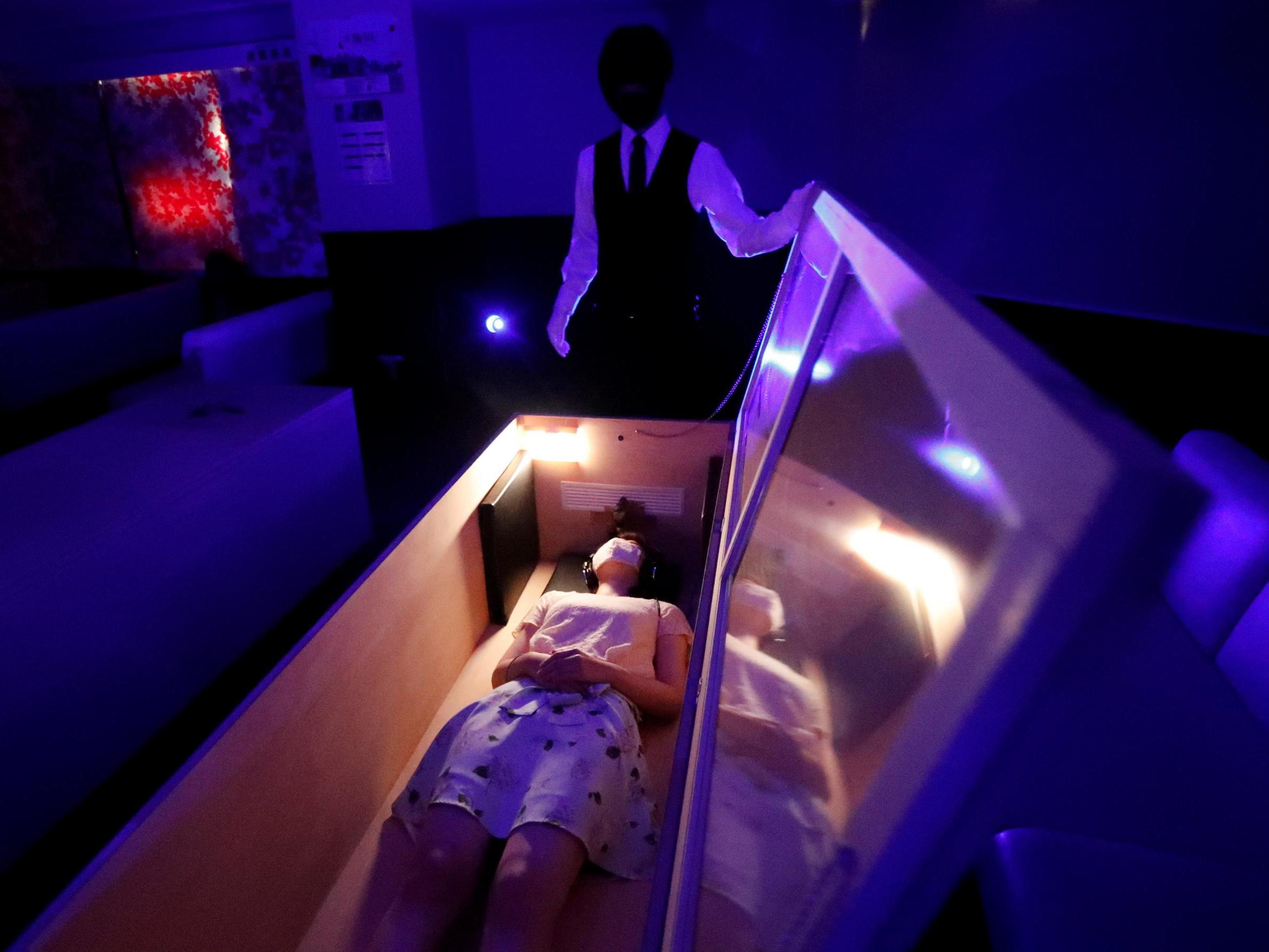 A participant lies inside a mock coffin with plastic shields to maintain social distancing amid the spread of the coronavirus