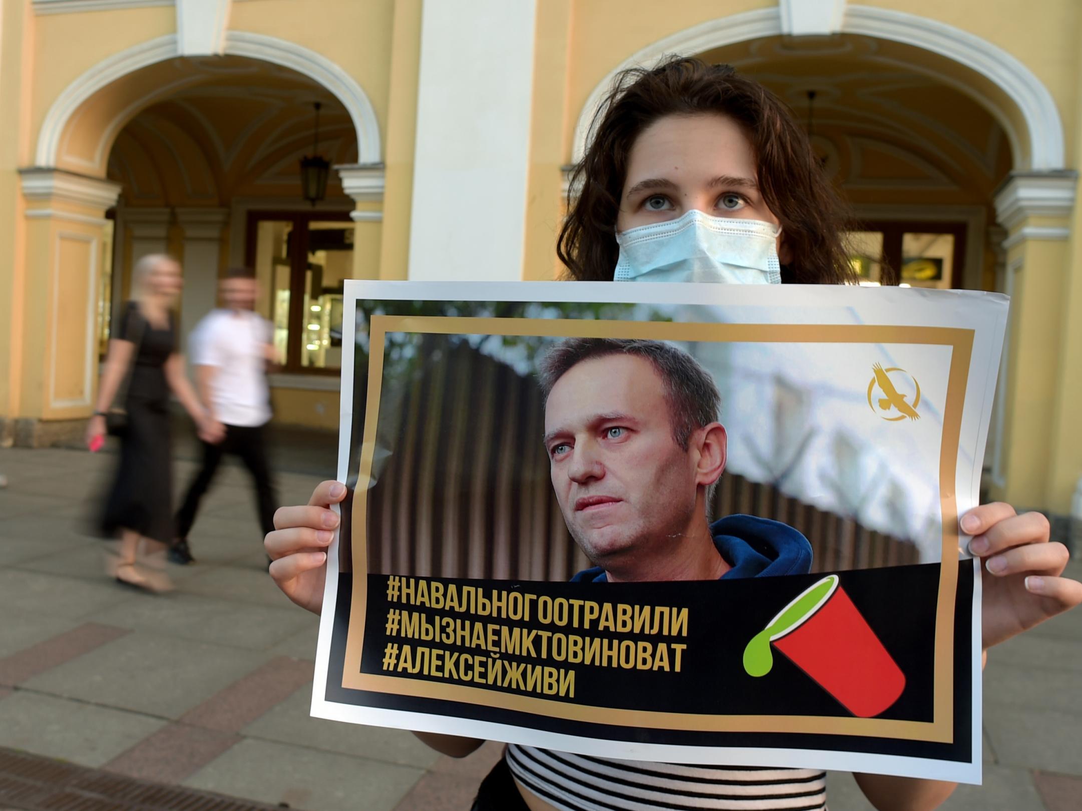 A woman holding a placard with an image of Navalny expresses support for the opposition leader after he was rushed to intensive care in Siberia