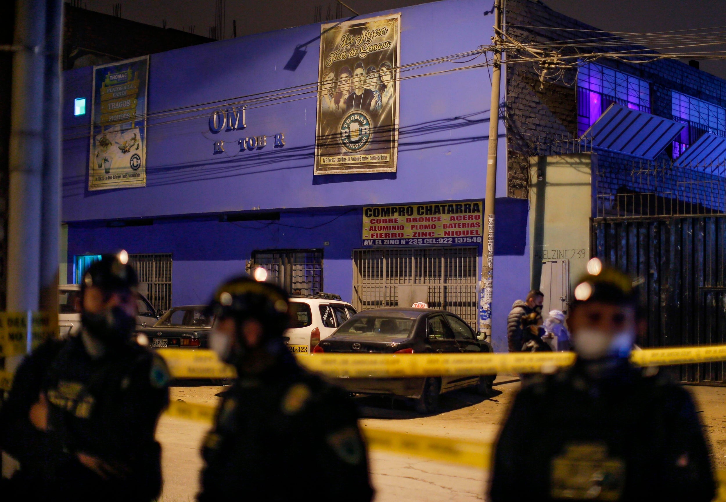 Police officers stand guard outside the nightclub in Lima after the raid