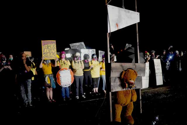 Protestors guillotine a teddy bear wearing a gas mask in Portland