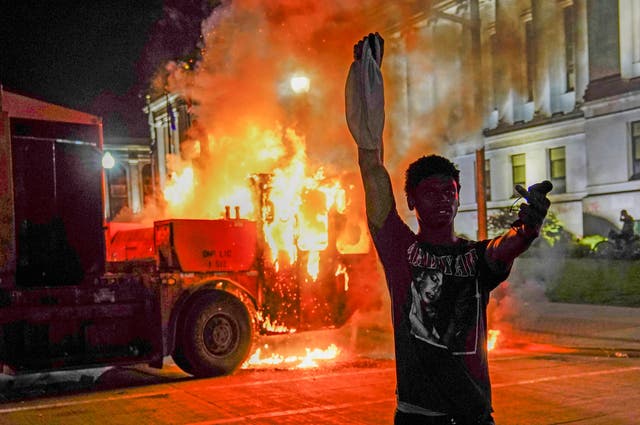 A protester in front of a burning truck in Kenosha, Wisconsin during unrest following the police shooting of Jacob Blake