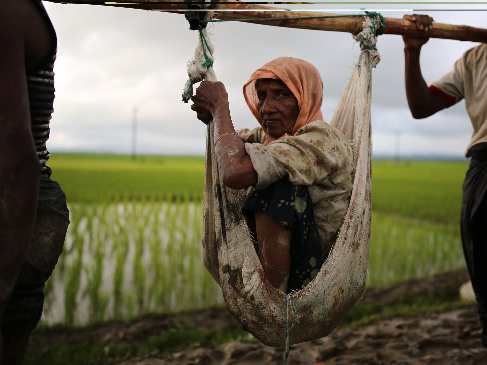 An elderly Rohingya woman is carried on poles as she flees Myanmar