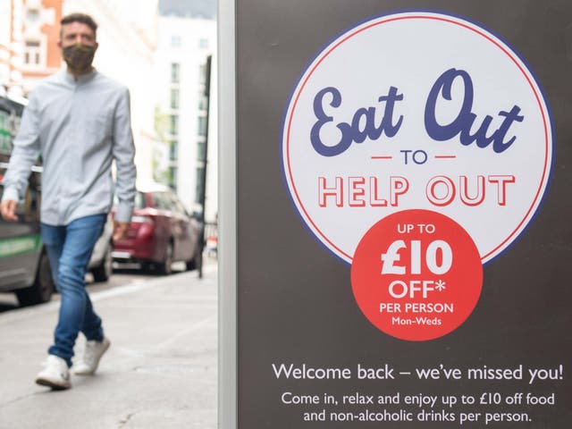 A man passing a sign advertising the 'Eat Out to Help Out' scheme, in Covent Garden