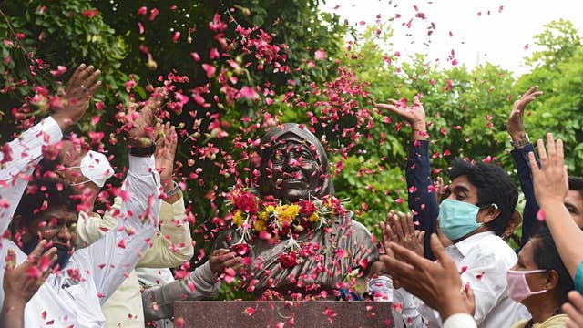 People scatter rose petals on a statue of Mother Teresa marking her 110th birth anniversary in Ahmedabad