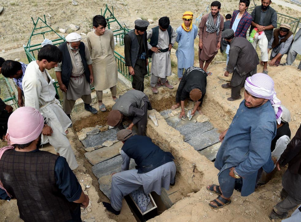 Relatives of victims cover graves with stones during a burial ceremony after people died in the flash floods that affected the area at Sayrah-e-Hopiyan in Charikar, Parwan province