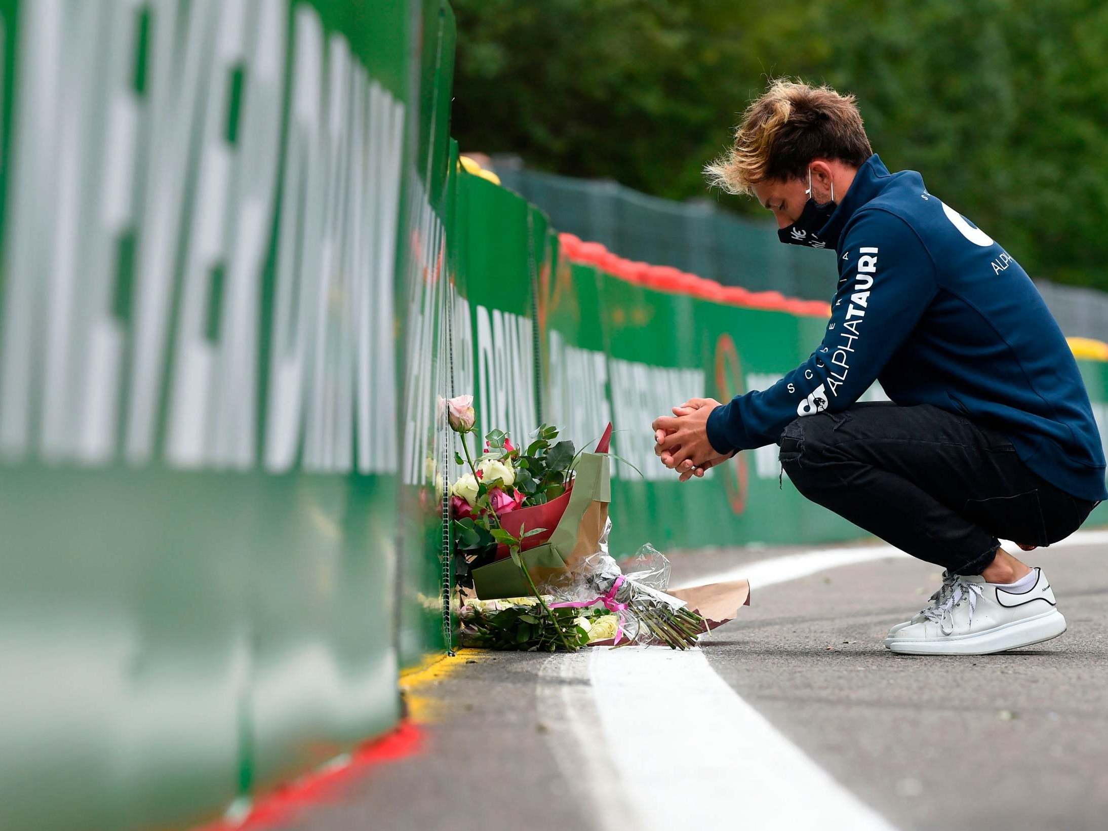 AlphaTauri's Pierre Gasly places a bouquet of flowers at the site of Anthoine Hubert's fatal accident nearly a year on
