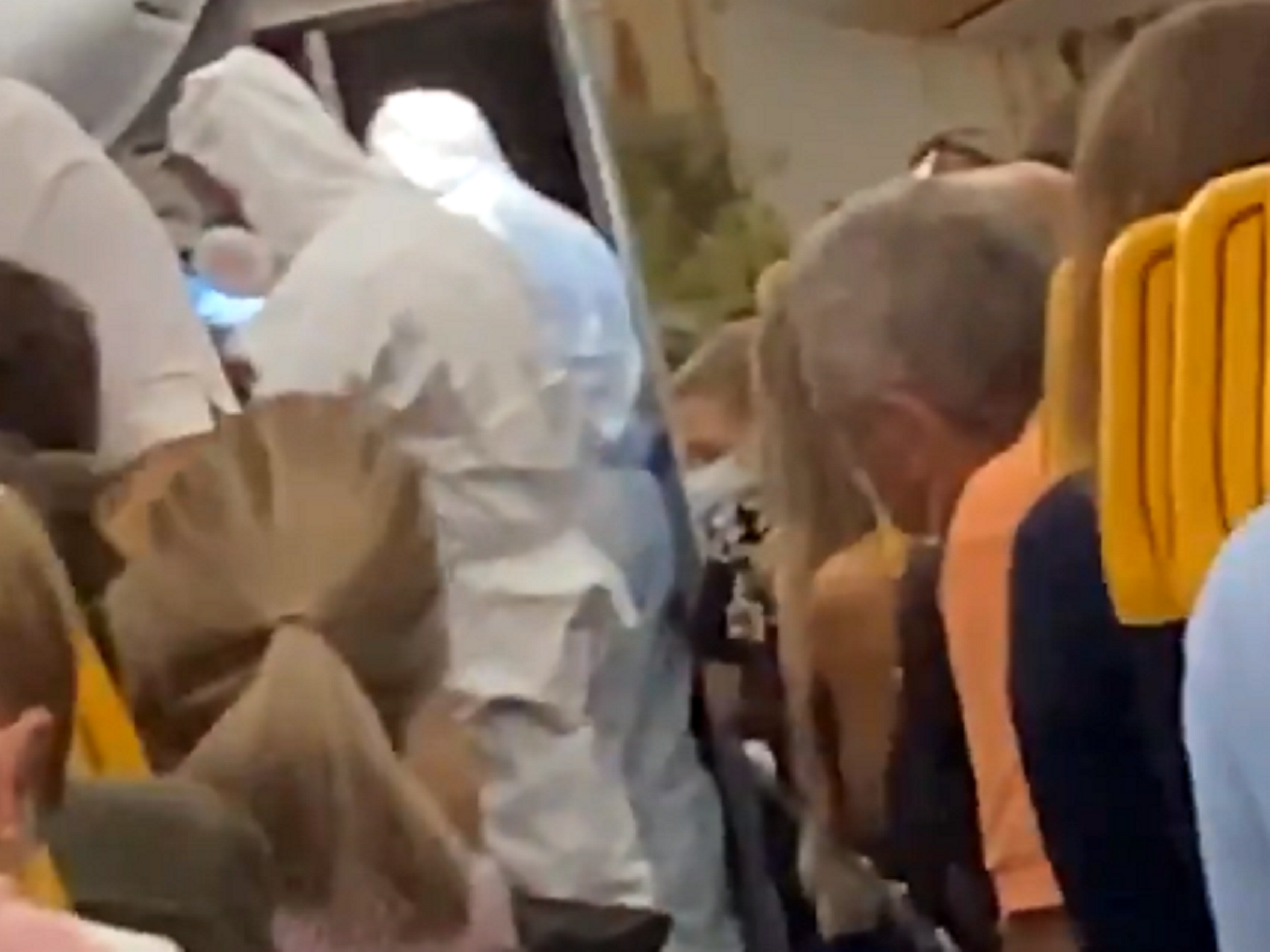 Still image taken from video posted on Twitter by @FionnMurphy10 of officials in hazmat suits removing two passengers from a Ryanair flight at Stansted Airport after one of them tested positive for coronavirus.