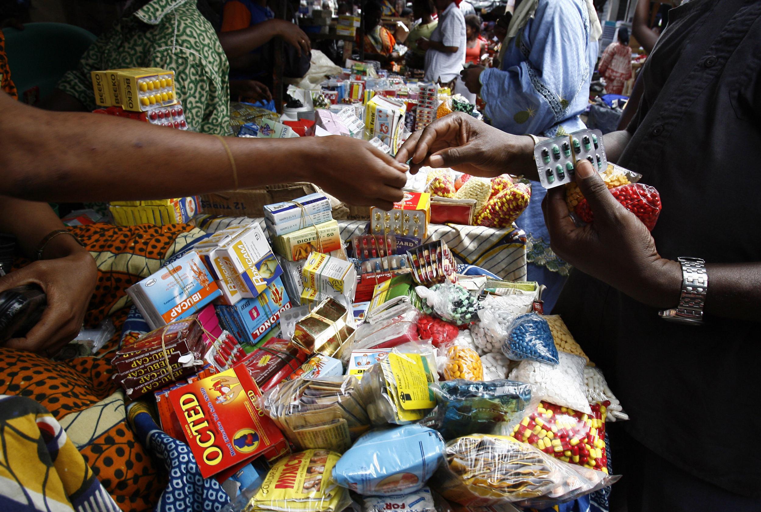 Customers haggle over smuggled, counterfeit medicine at a market in Abidjan, Ivory Coast