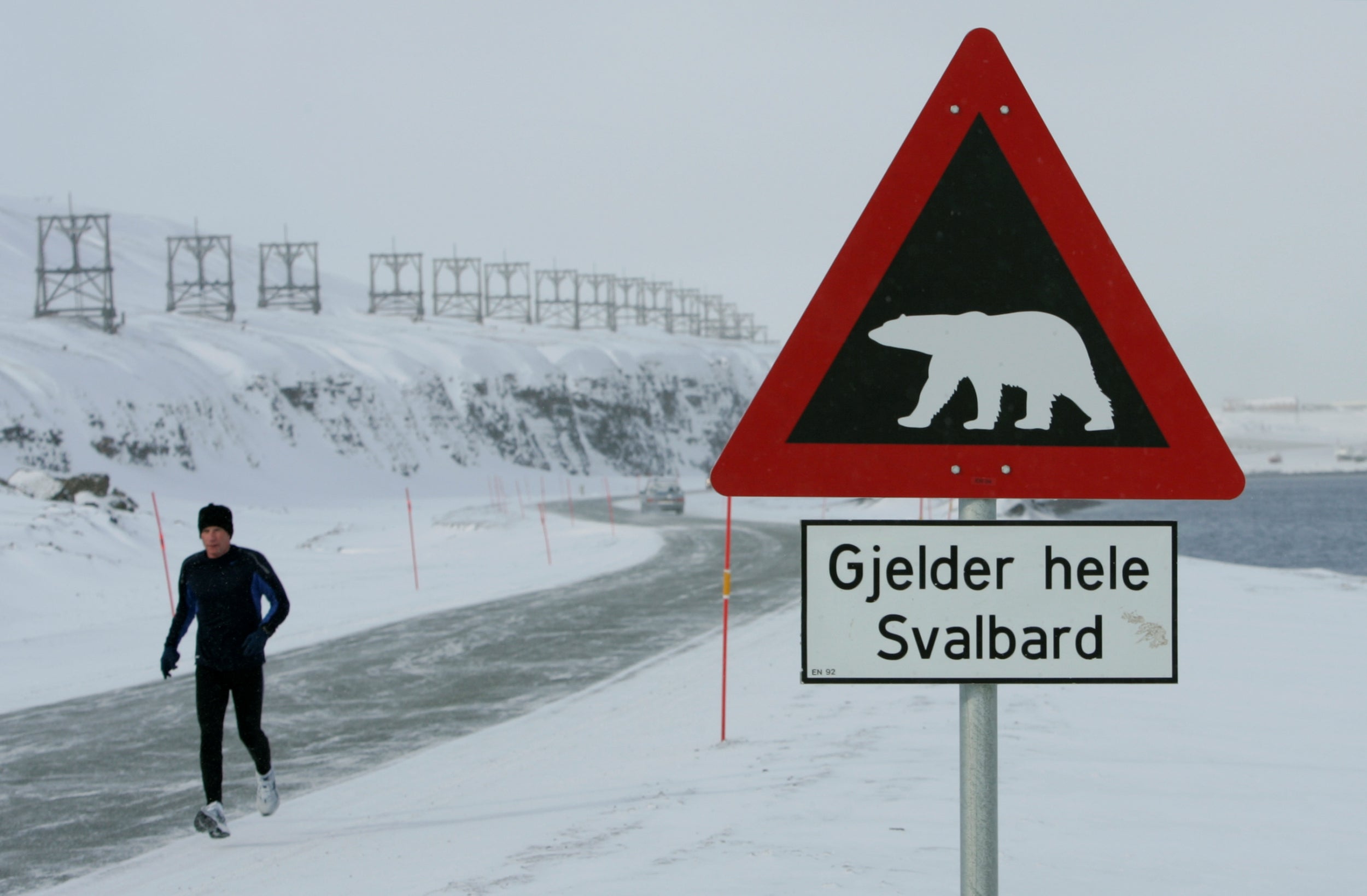 A runner passes a sign warning of the dangers of polar bears on the Norwegian Arctic archipelago of Svalbard