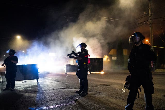 Portland police disperse a crowd after protesters set fire to the Portland Police Association (PPA) building early in the morning August 29, 2020