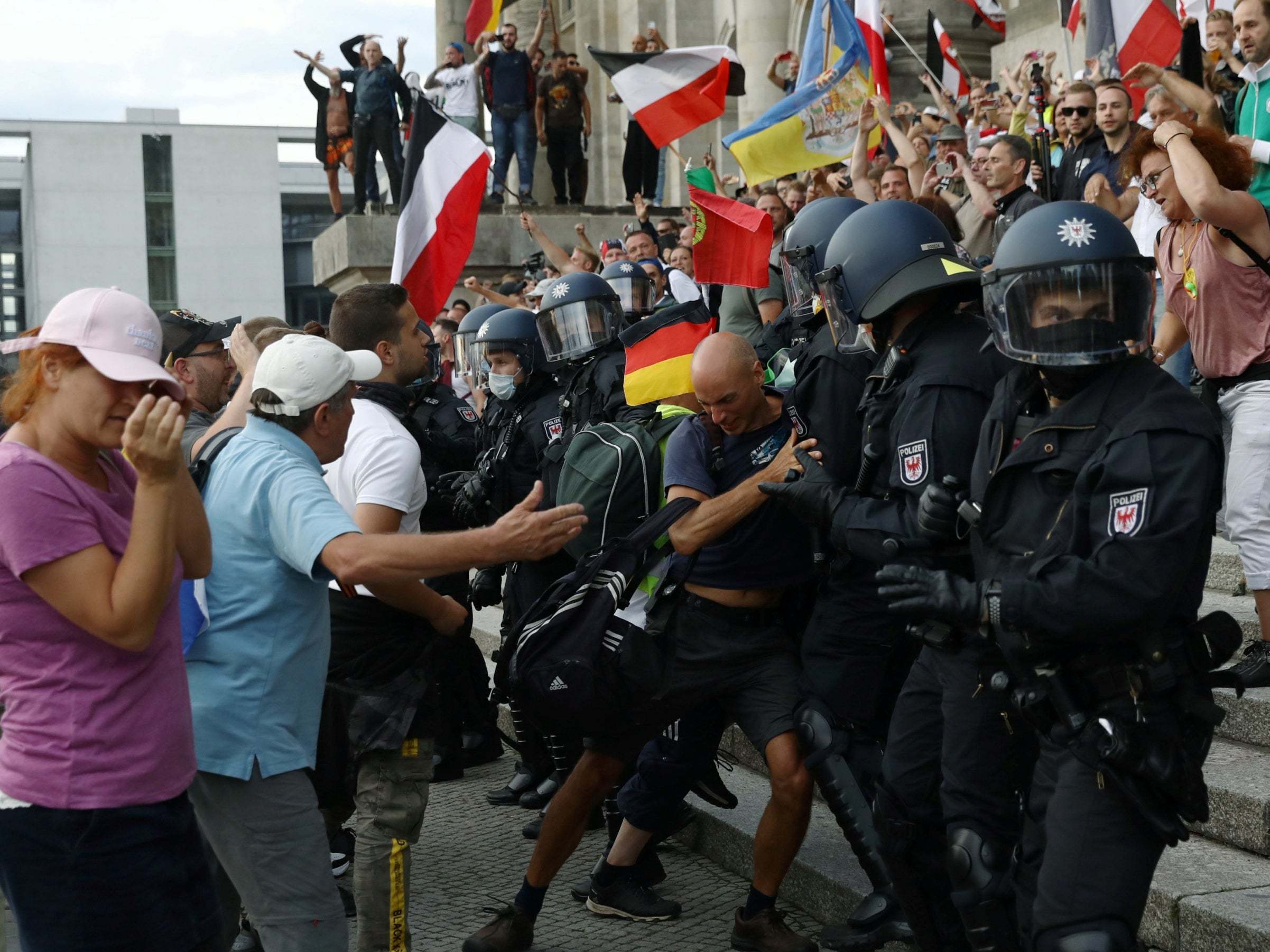 Police scuffle with protesters in front of the Reichstag building in Berlin, Germany.