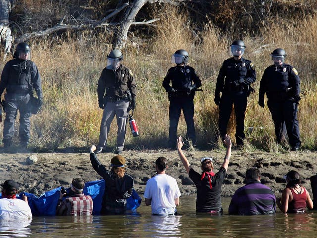 Dozens of protestors demonstrating against the expansion of the Dakota Access Pipeline wade in cold creek waters confronting local police, near Cannon Ball, North Dakota in November 2016