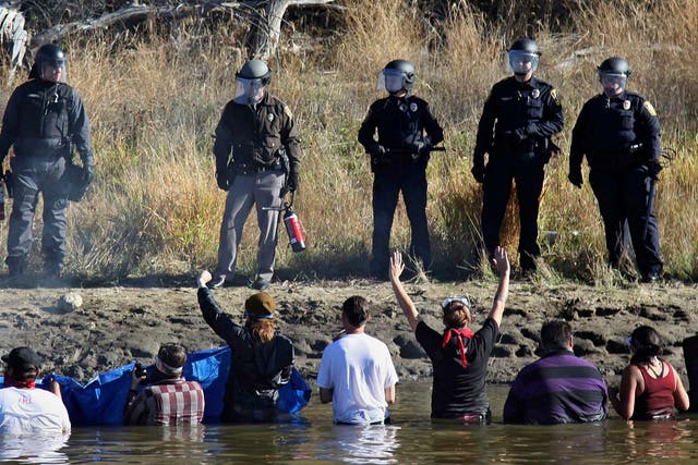 Dozens of protestors demonstrating against the expansion of the Dakota Access Pipeline wade in cold creek waters confronting local police, near Cannon Ball, North Dakota in November 2016
