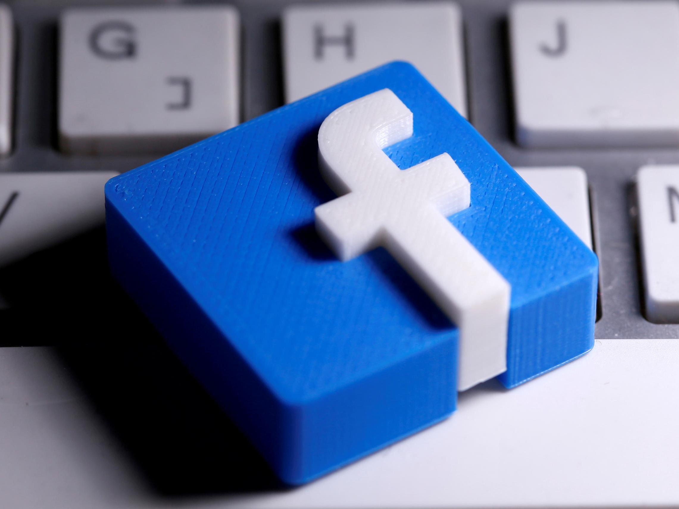 Se ve un logotipo de Facebook impreso en 3D colocado en un teclado en esta ilustración