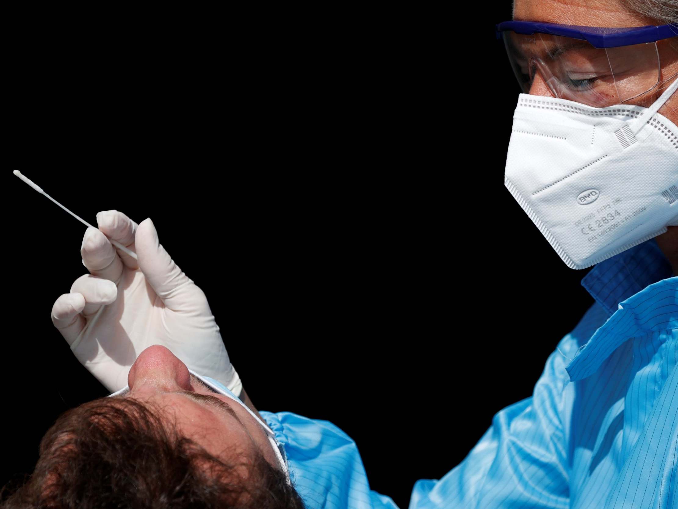 A health worker prepares to administer a nasal swab to a patient at a testing site in Paris