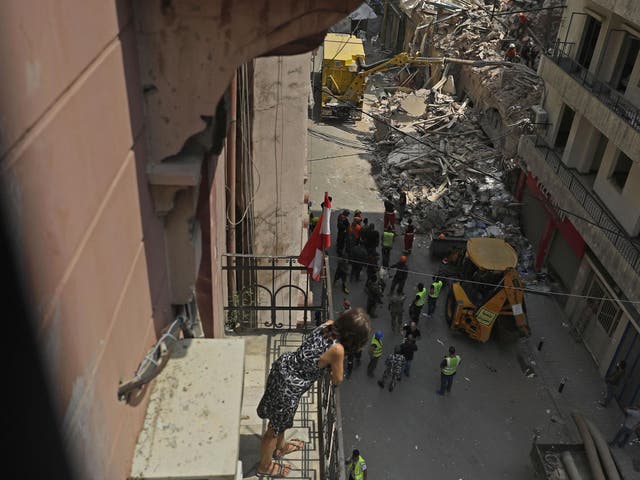 Rescue workers prepare to vacuum debris from a badly damaged building