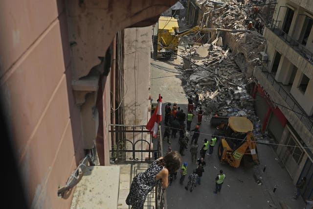Rescue workers prepare to vacuum debris from a badly damaged building