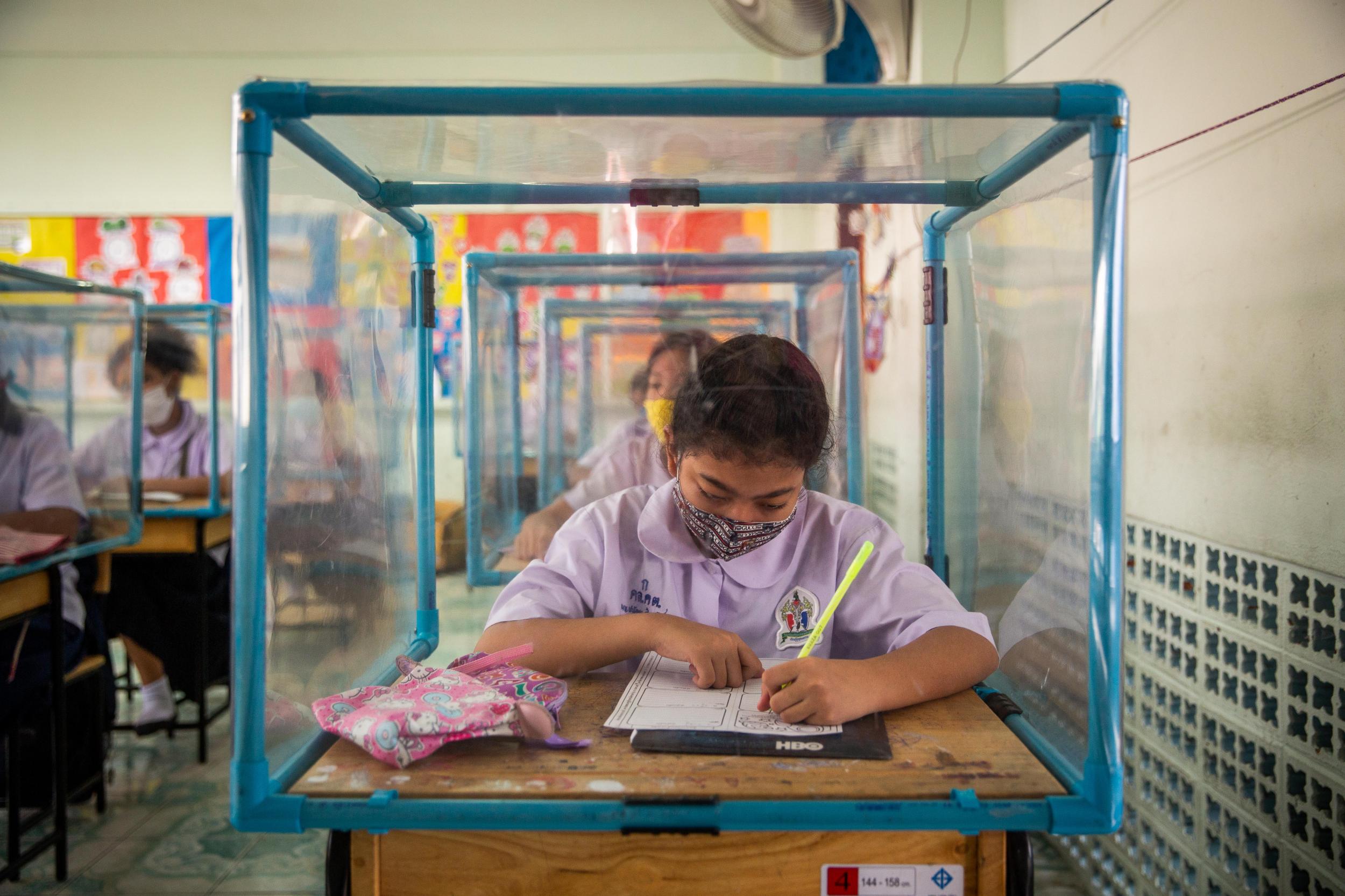 Thai students wear face masks and sit at desks with plastic screens used for social distancing at the Wat Khlong Toey School on August 10, 2020