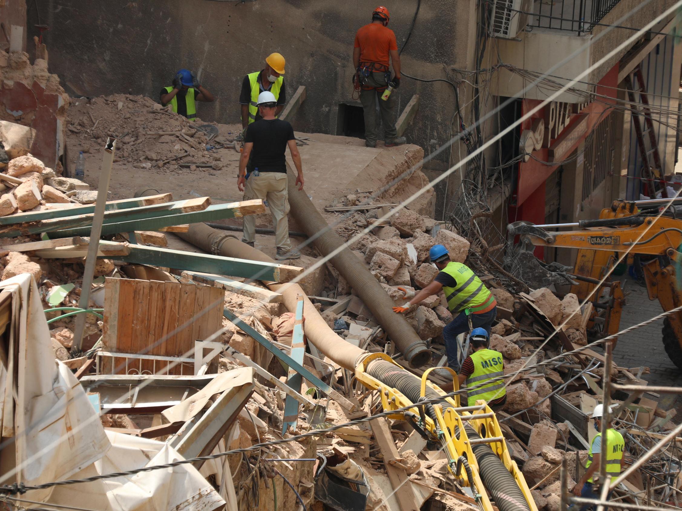 Search teams look for survivors in the rubble of a building destroyed in the Beirut blast