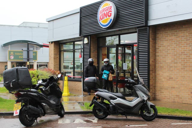 <p>A Deliveroo driver picks up a food order from a Burger King restaurant</p>