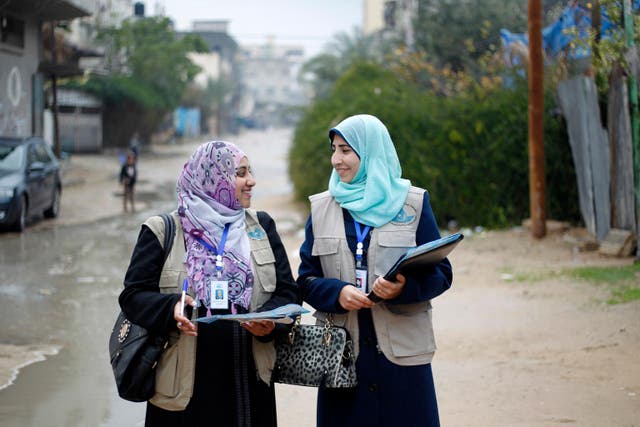 Dos mujeres que trabajan para el servicio de agua de los municipios costeros de Gaza distribuyen folletos de información en la ciudad de Khan Younis (U