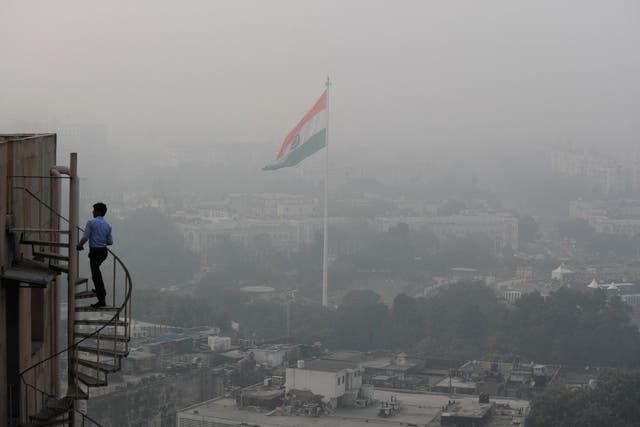 <p>An Indian man walks up stairs as Delhi’s skyline is seen enveloped in smog and dust</p>