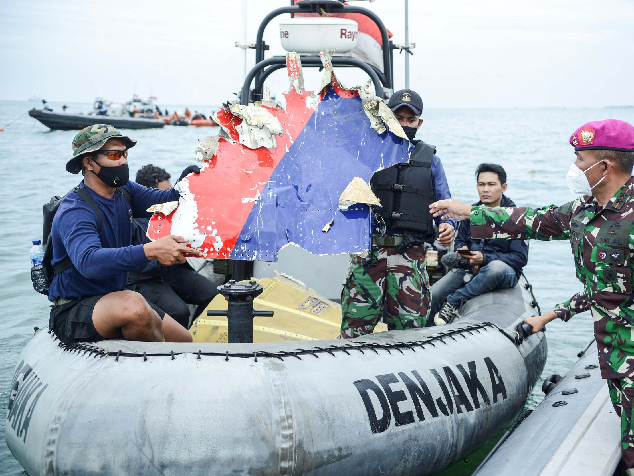 Indonesian navy personnel carry debris believed to be from the missing Sriwijaya Air plane in January 2021