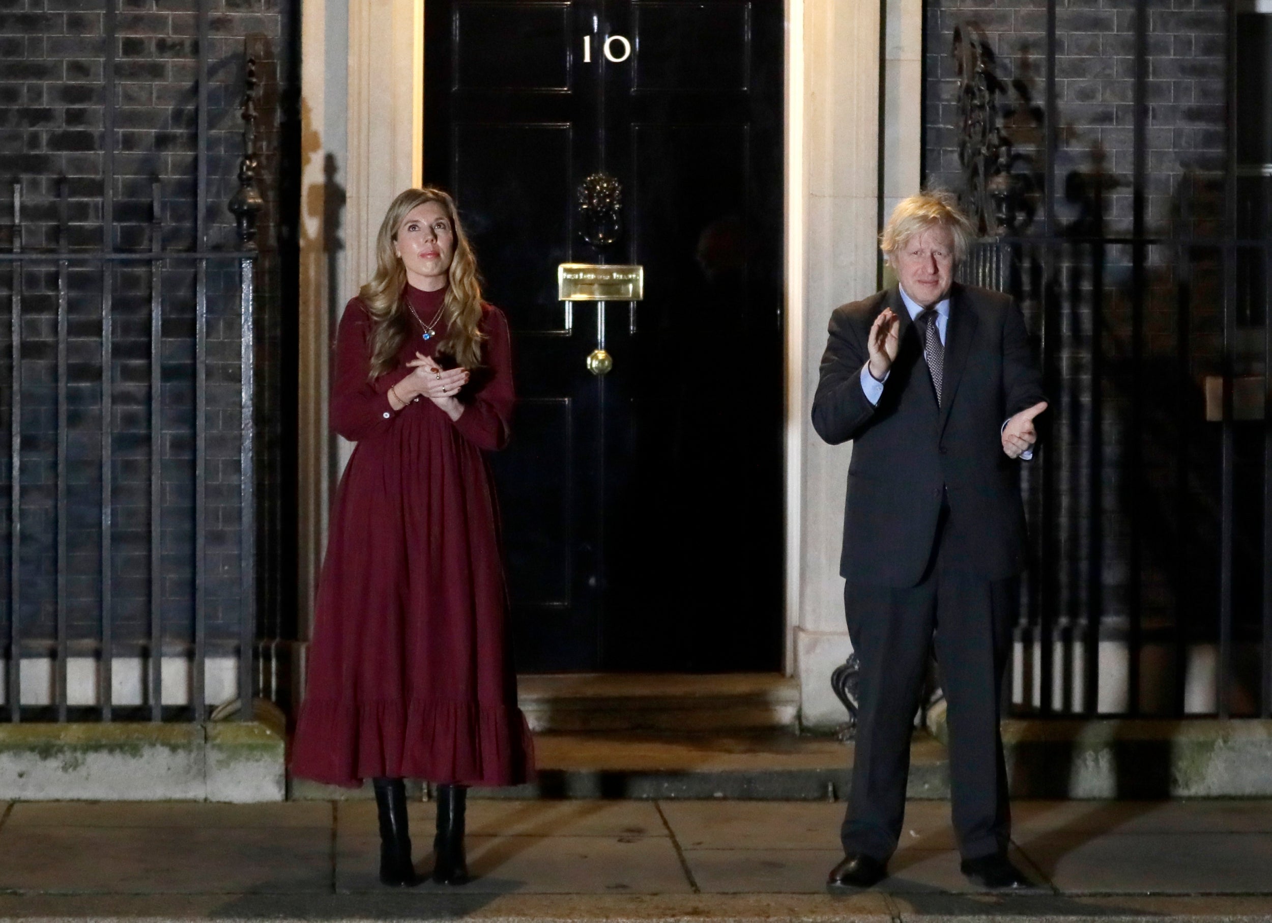 Former Prime Minister Boris Johnson and his partner Carrie Symonds clap on the doorstep of 10 Downing Street to honour Captain Tom Moore after his death