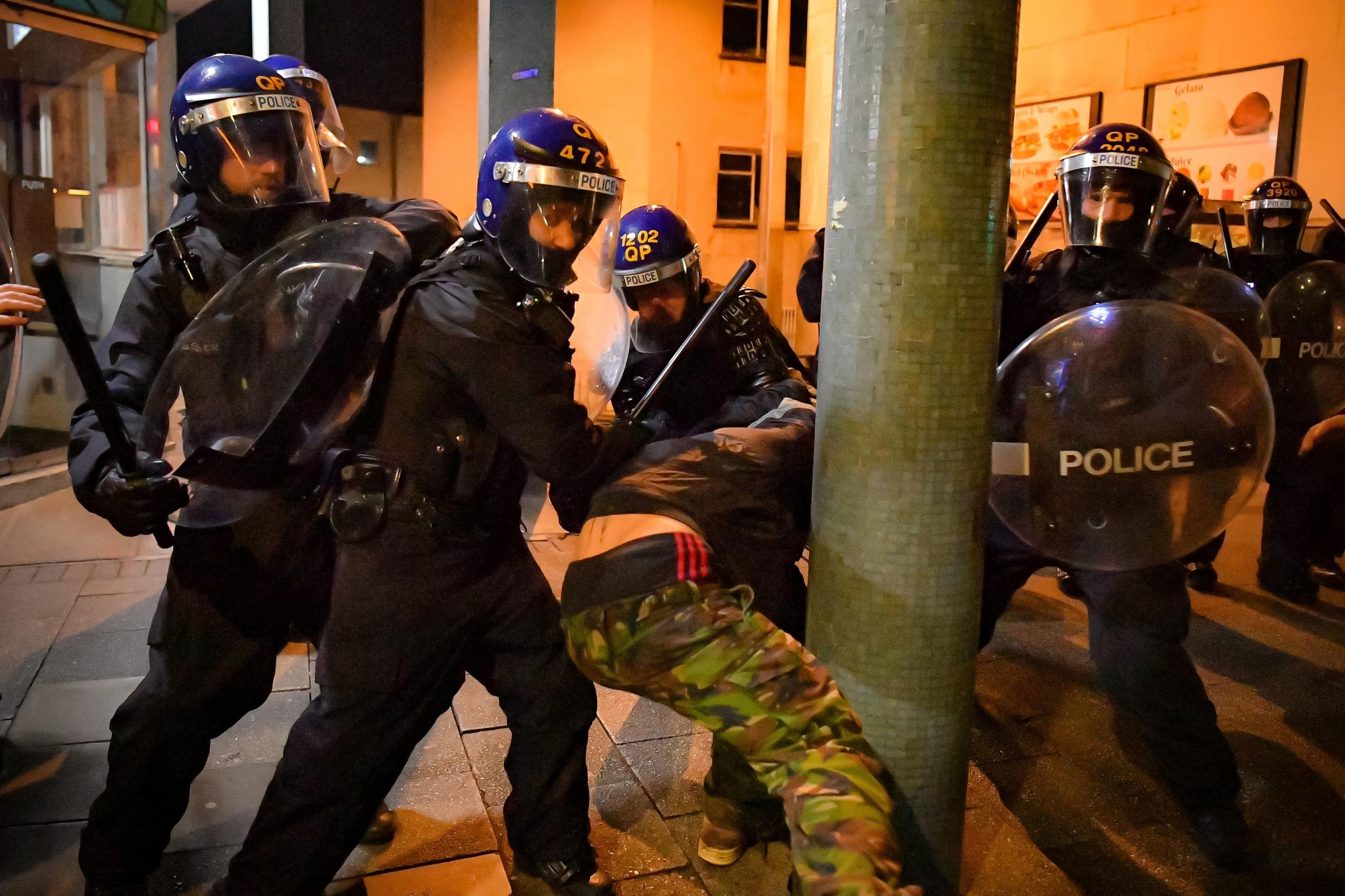 Police officers detain a man as they move in on demonstrators in Bristol in March