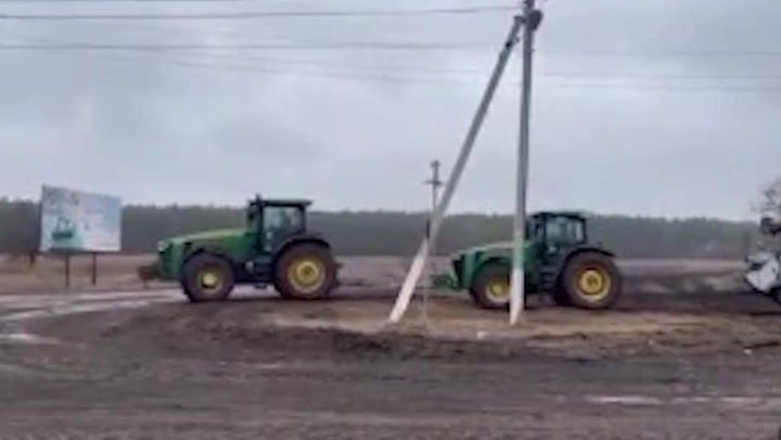 Ukrainian farmers tow abandoned Russian tank away with tractors